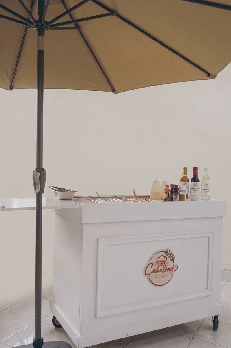 The Cakuterie cart with its logo panel, set up under a patio umbrella
