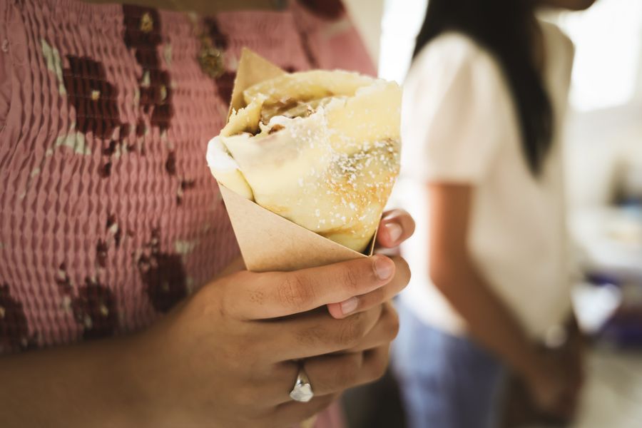 A guest holding a freshly made crepe in a paper cone