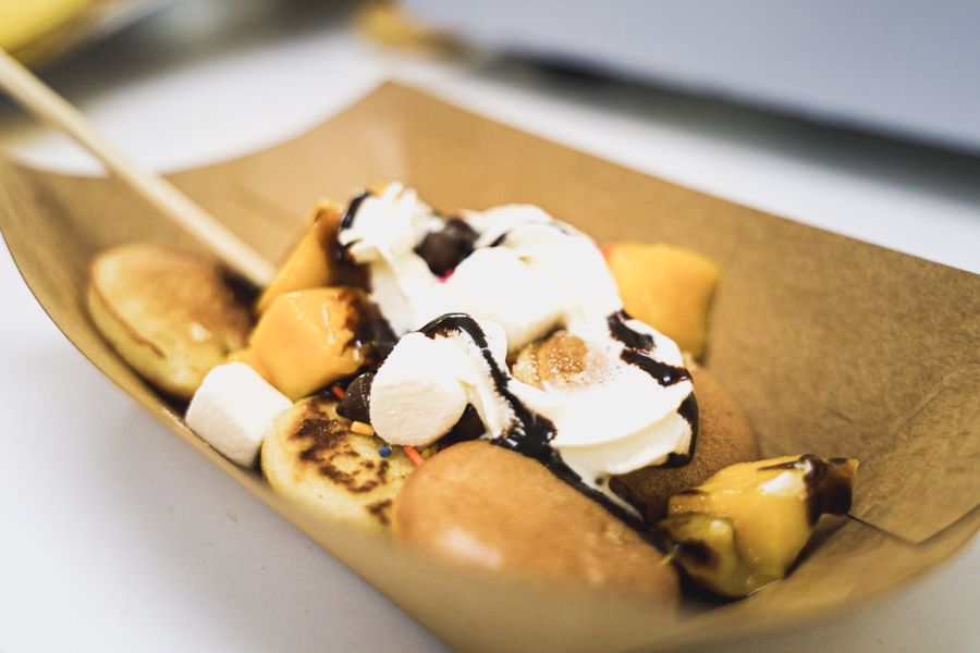 Mini pancakes with mango, whipped cream, chocolate drizzle and marshmallows